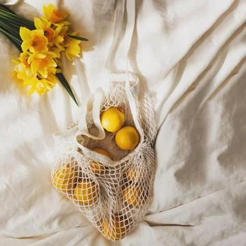 Spring flat lay with lemons and yellow flowers lying on the bed Stock Photos