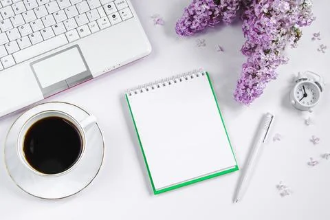 Spring flatlay. Notepad, laptop, lilac flowers and cup of coffee on light Stock Photos