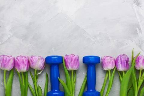 Spring flatlay sport composition with blue dumbbells and purple tulips. Stock Photos