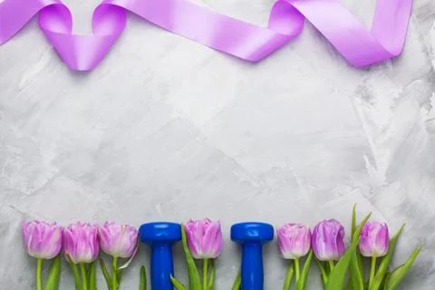 Spring flatlay sport composition with blue dumbbells and purple tulips. Stock Photos