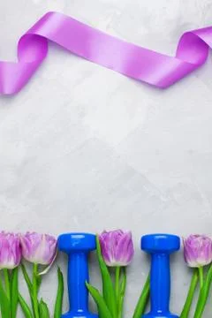 Spring flatlay sports composition with blue dumbbells and purple tulips. Stock Photos