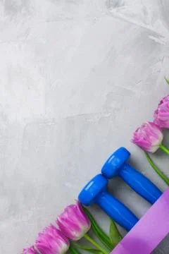 Spring flatlay sports composition with blue dumbbells and purple tulips. Stock Photos