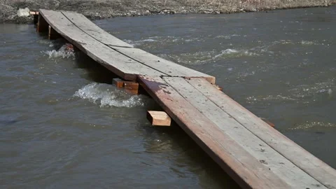 Spring flood water rushing under a simple wooden walking and cycling bridge.  Stock Footage 153097155