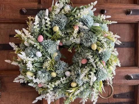 Spring floral wreath with decorative Easter eggs on a wooden door Foto stock
