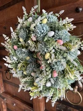 Spring floral wreath with decorative Easter eggs on a wooden door Stock Photos