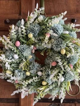 Spring floral wreath with decorative Easter eggs on a wooden door Stock Photos