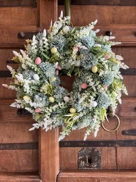 Spring floral wreath with decorative Easter eggs on a wooden door Stock Photos