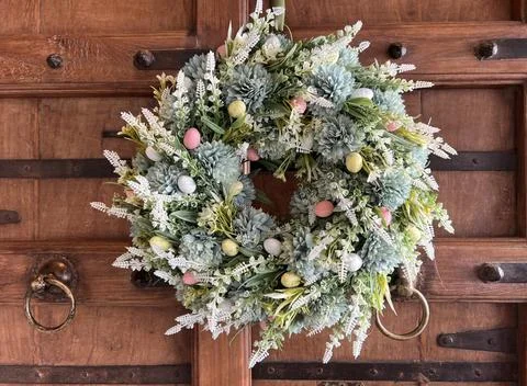 Spring floral wreath with decorative Easter eggs on a wooden door Foto stock
