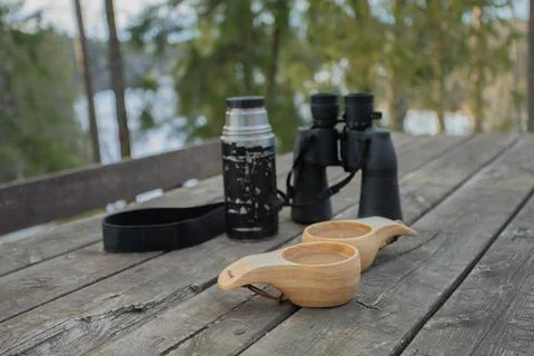 Spring forest. On the table are binoculars, a thermos and mugs of coffee. Stock Photos