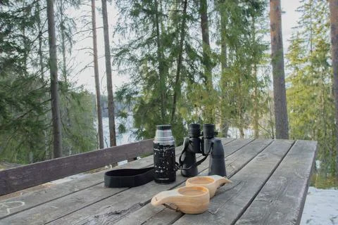 Spring forest. On the table are binoculars, a thermos and mugs of coffee. Stock Photos