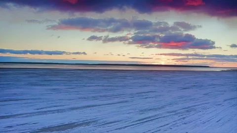 Spring ice melts, exposing open water against a red sunset backdrop. Aerial Stock Footage 257762668