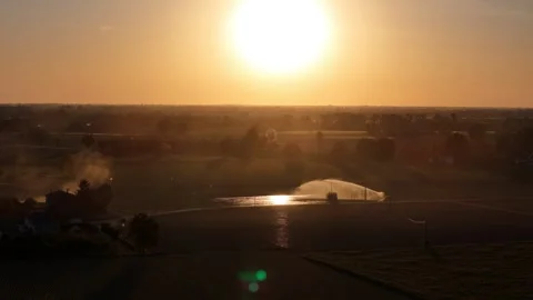 Spring irrigation and tractor dust at sunset in Po Valley farmland Italy drone Stock Footage 335966081