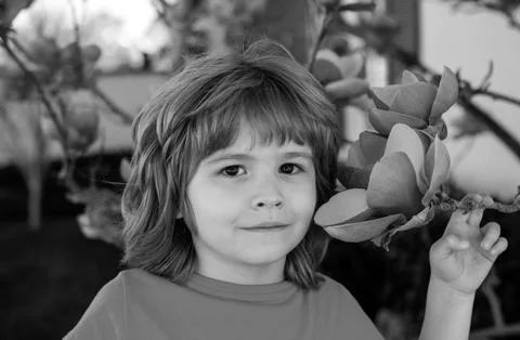 Spring kid with flower tree. Cute child in blossom garden. Happy boy at park Fotos Stock