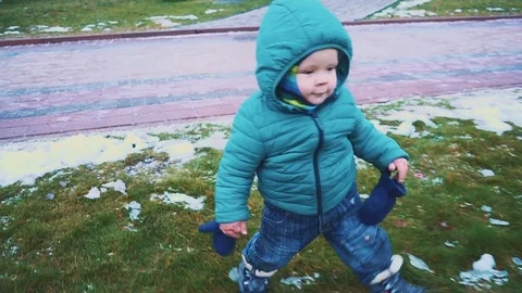 Spring. kid running down the sidewalk, grass and melting snow. Видео 83481497