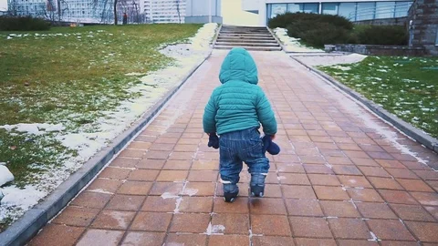 Spring. kid running down the sidewalk, grass and melting snow. Stock Footage 83482344