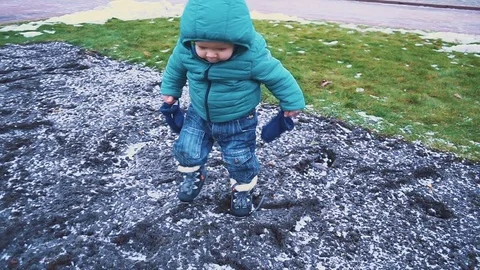Spring. kid running down the sidewalk, grass, melting snow and falls to the Stock Footage 83484710