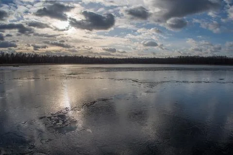 Spring lake covered with thin transparent cracking ice. Foto stock