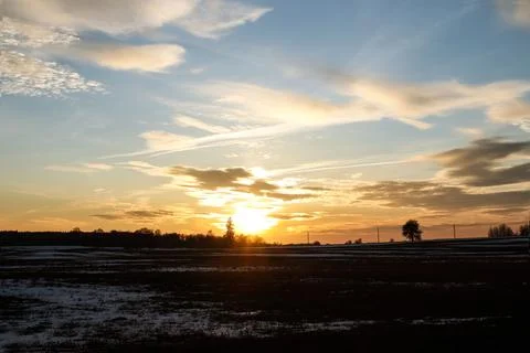 Spring landscape: setting sun over the edge of a forest and field Stock Photos