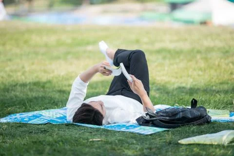 Spring, man looking at a book on the grass. Stock Photos