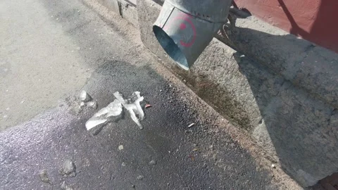 Spring melt water flows from the drainpipe onto the asphalt with ice Stock Footage 175958015