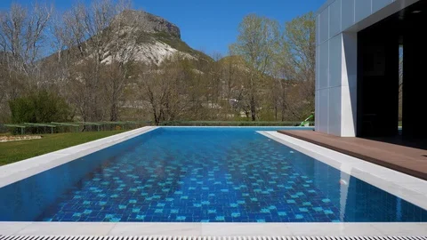 Spring. Modern house with pool in the mountains. Man mowing the lawn Stock Footage 129503659