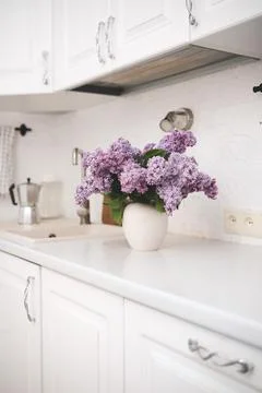 Spring morning in light kitchen: bouquet of lilac flowers in white kitchen. Foto stock