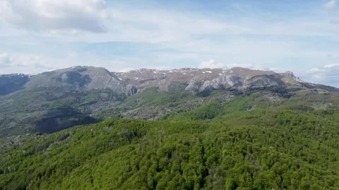 Spring mountain landscape with forest below and rocky peaks above. 库存影片 335469857