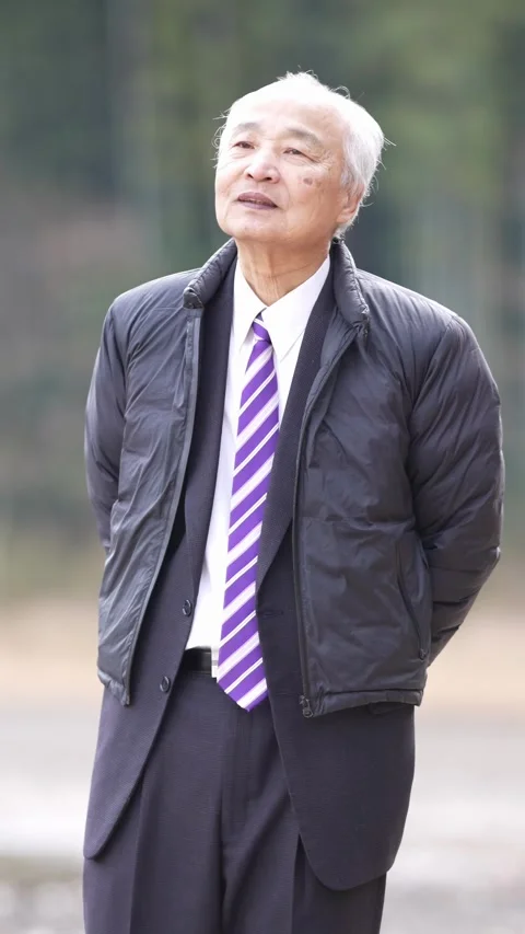 In a spring natural park with a pond and bamboo grove, a Japanese man in his 70s Stock Footage 307828358