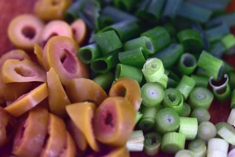 Spring onions and olives chopped on wooden plate. Food photography. 库存照片