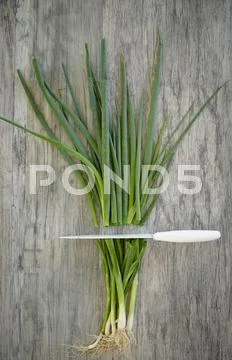 Spring Onions Being Cut On Wooden Table