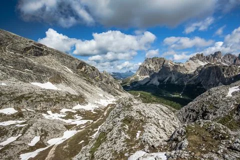 Spring panorama of the green meadows of the Dolomites with snow and pink rock Stock Photos