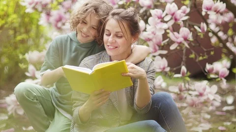 Spring portrait of mom and son. A woman with a book in her arms hugs with a Stock Footage 118910872