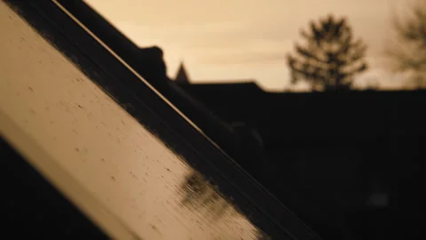 Spring rain pouring lighty on window in sunset golden hour Stock Footage 303850241