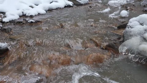 Spring runoff in a small stream. The water level rises and spreads wider. Snow Stock-Footage 329552990