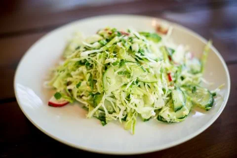Spring salad with cabbage cucumbers and radishes on a wooden background. Stock Photos