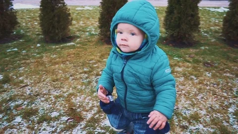 Spring. Steadicam shot of kid running down the sidewalk, grass and melting snow Video stock 83474335