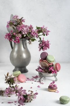Spring still life with colored macaroons and pink apple tree flowers in a pewter Stock Photos
