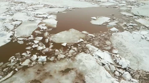 The spring sun is reflected in the dirty river water. Cracked white ice floes Stock Footage 153026161