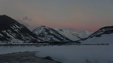 Spring sunrise over snow-covered peaks leads to day break in the valley Stock Footage 107614347