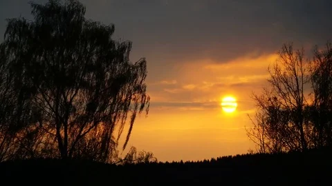 Spring sunset timelaps with dramatic clouds, orange colors and tree silhouette Stock Footage 75060098