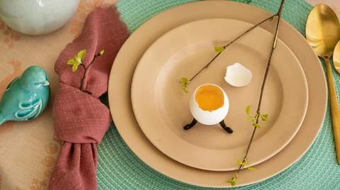 Spring table set for Easter - a chicken egg and a twig with the first leaves on Stock Photos