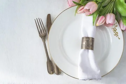 Spring table setting; Bouquet of pink tulips, vintage fork and knife, white.. Stock Photos