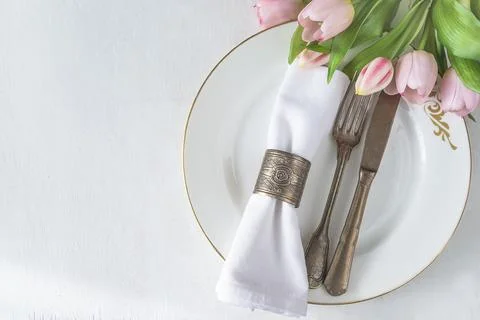 Spring table setting; Bouquet of pink tulips, vintage fork and knife, white.. Stock Photos