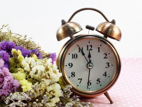 Spring time with alarm clock and statice flowers bouquet background Foto stock