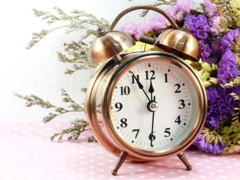Spring time with alarm clock and statice flowers bouquet background Foto stock