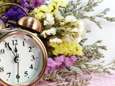 Spring time with alarm clock and statice flowers bouquet background Foto stock