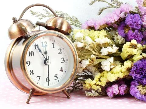 Spring time with alarm clock and statice flowers bouquet background Stockfoto's