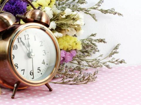 Spring time with alarm clock and statice flowers bouquet background Foto stock