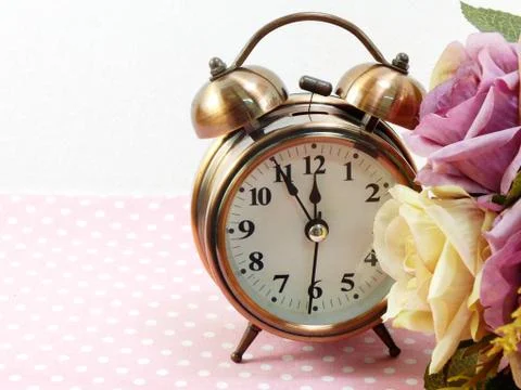 Spring time with alarm clock and artificial flowers bouquet background Stockfoto's