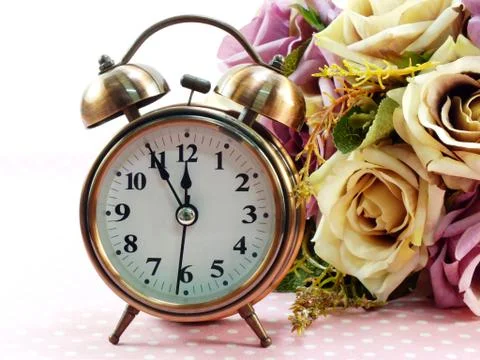 Spring time with alarm clock and artificial flowers bouquet background 库存照片